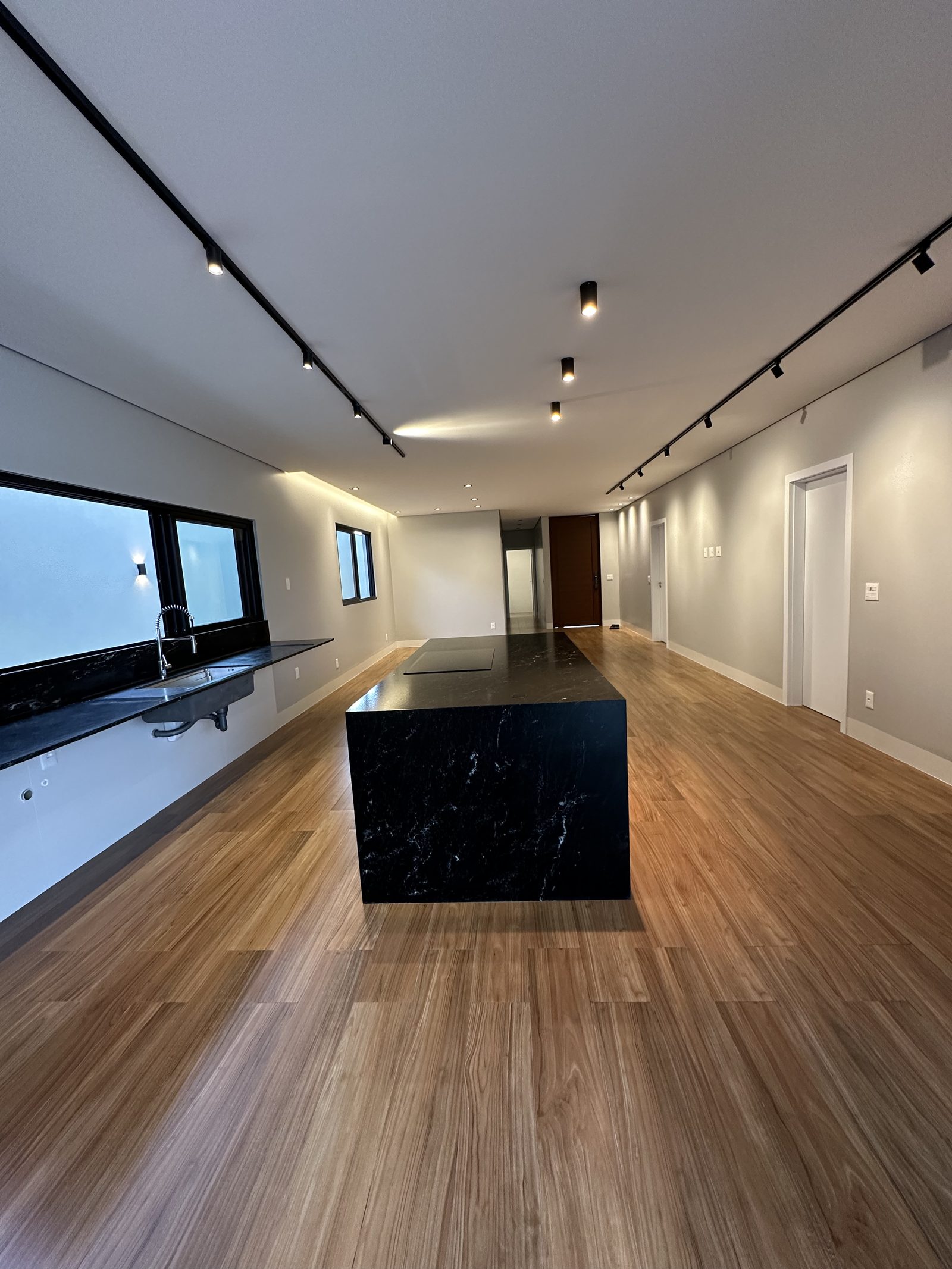 Cozinha com ilha de granito preto e piso de madeira