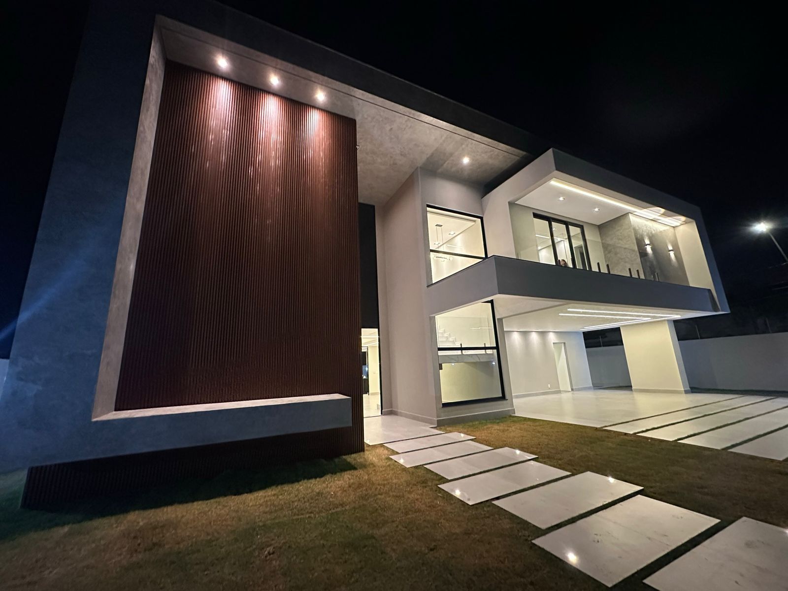 Fachada noturna com ripado de madeira — AJ Mendes Construtora